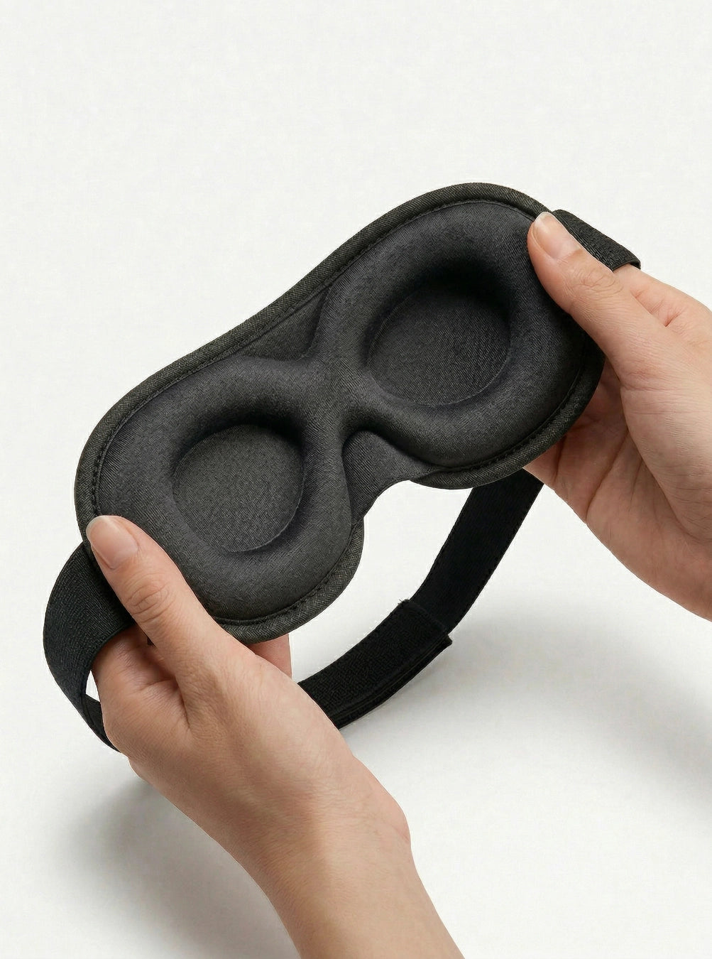 Black sleep mask held by hands on a white background, stormgrey