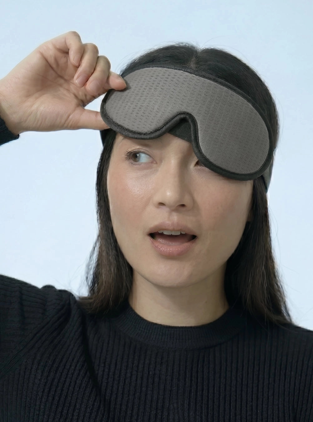 Person wearing a gray sleep mask against a light blue background, stormgrey